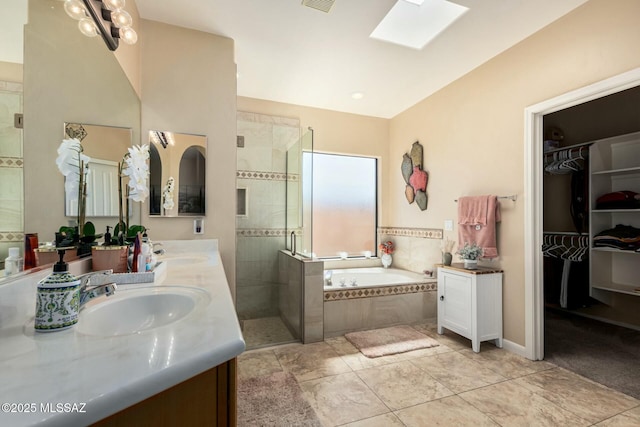 bathroom featuring a sink, a bath, a stall shower, and a skylight