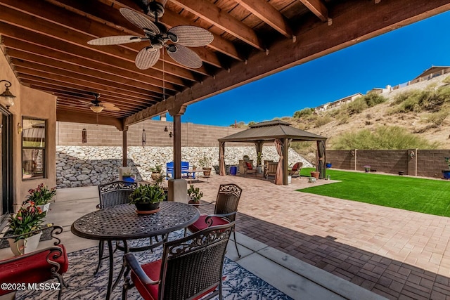 view of patio / terrace featuring a gazebo, a fenced backyard, ceiling fan, and outdoor dining area