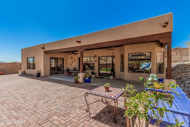 rear view of house featuring a patio, ceiling fan, fence, and stucco siding