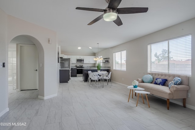 living room with a ceiling fan, arched walkways, and baseboards