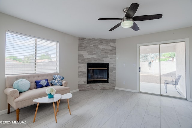 living room with baseboards, a ceiling fan, a tile fireplace, and plenty of natural light