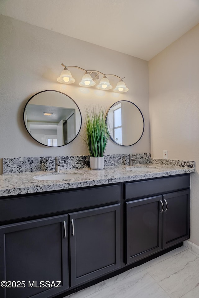 bathroom with double vanity, marble finish floor, and a sink