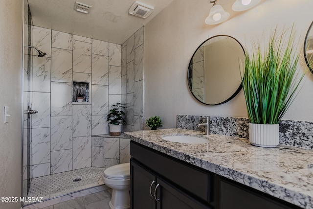 full bathroom with toilet, vanity, marble finish floor, and tiled shower