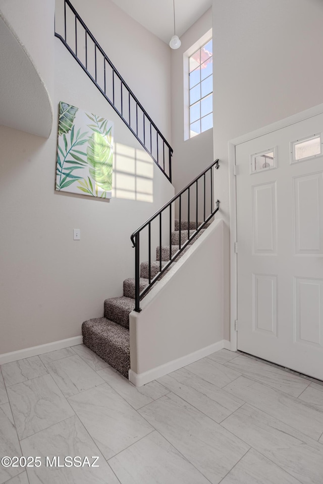 foyer with baseboards, stairs, a high ceiling, and marble finish floor