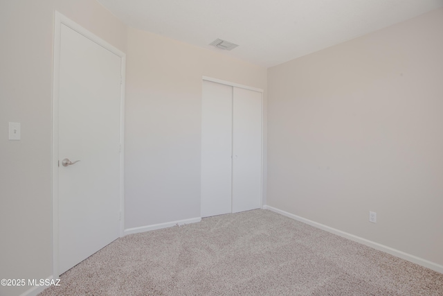 carpeted spare room featuring baseboards and visible vents