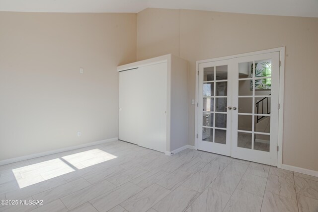 spare room featuring baseboards, high vaulted ceiling, and french doors