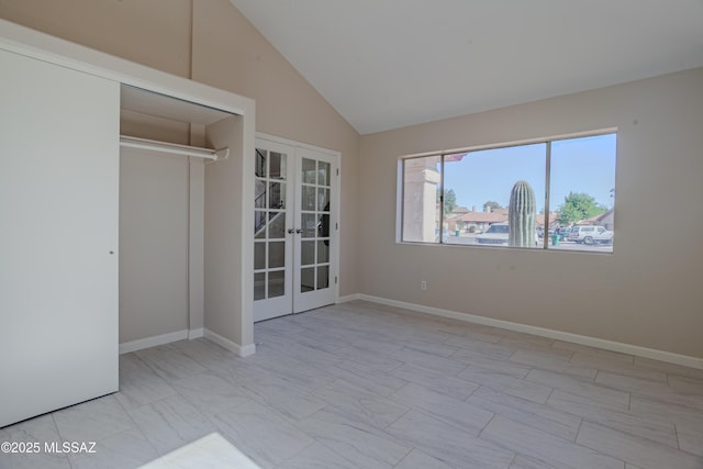 empty room featuring vaulted ceiling, french doors, and baseboards