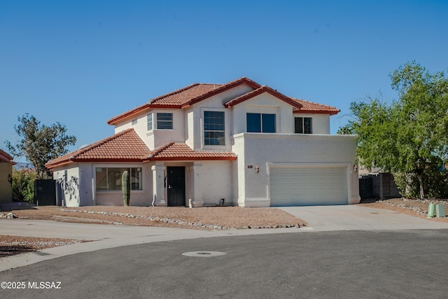 mediterranean / spanish-style home with driveway, fence, a tiled roof, stucco siding, and a garage
