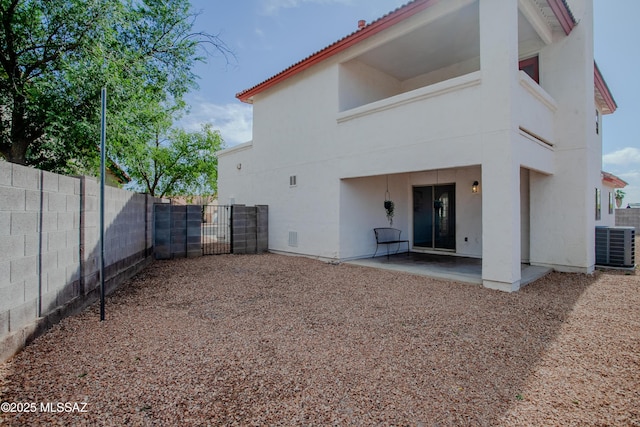 back of property with fence, a gate, a patio area, stucco siding, and central AC unit