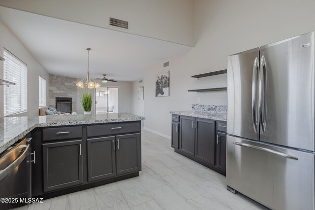 kitchen with open shelves, a large fireplace, appliances with stainless steel finishes, visible vents, and a peninsula