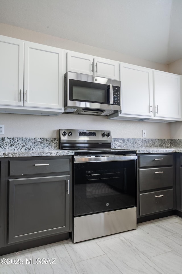 kitchen featuring white cabinetry, marble finish floor, appliances with stainless steel finishes, and light stone counters