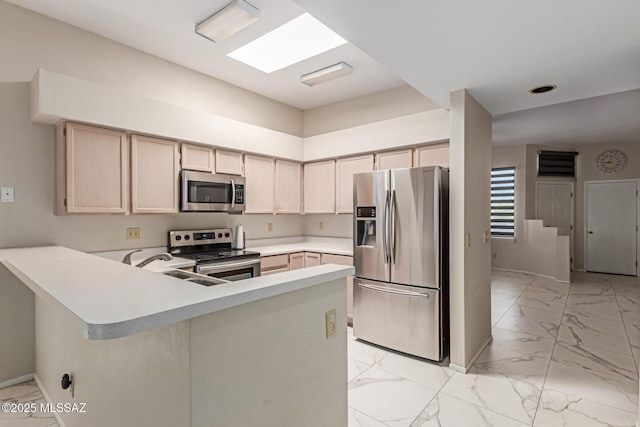 kitchen featuring appliances with stainless steel finishes, light brown cabinets, light countertops, marble finish floor, and a peninsula