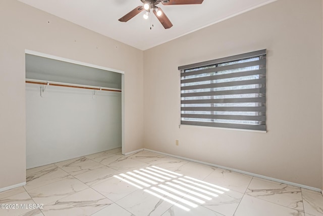 unfurnished bedroom with a closet, marble finish floor, and baseboards