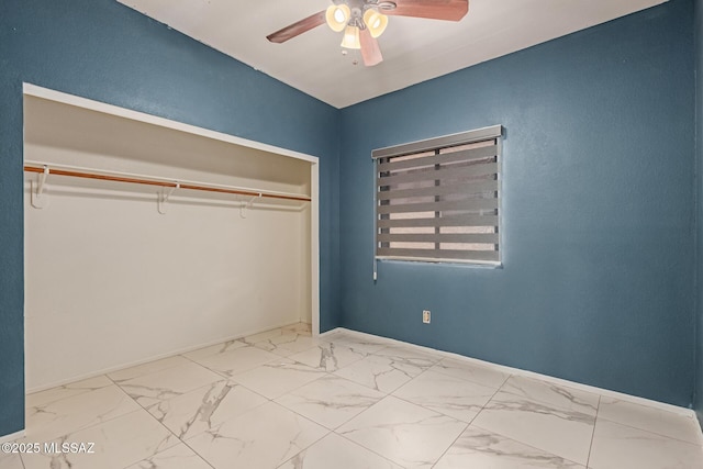 unfurnished bedroom featuring a closet, marble finish floor, ceiling fan, and baseboards