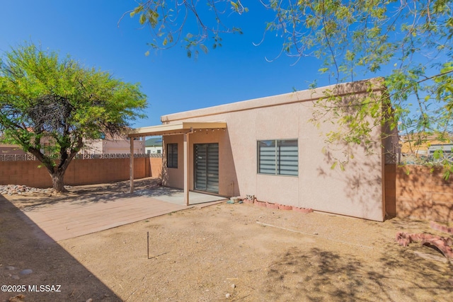 back of house featuring a patio, a fenced backyard, and stucco siding