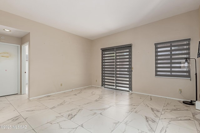 spare room with a healthy amount of sunlight, baseboards, and marble finish floor