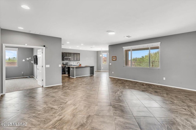 3156 S Three D Ct, Tucson, AZ 85713 - unfurnished living room with plenty of natural light, baseboards, recessed lighting, and a sink