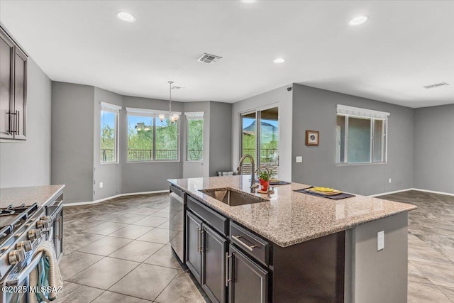 3156 S Three D Ct, Tucson, AZ 85713 - kitchen featuring a sink, light stone counters, a center island with sink, stainless steel appliances, and baseboards