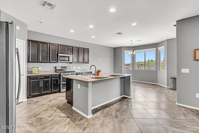 3156 S Three D Ct, Tucson, AZ 85713 - kitchen with stainless steel appliances, a chandelier, baseboards, light stone countertops, and a sink