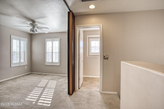 corridor featuring visible vents, a wealth of natural light, and light carpet