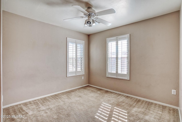 carpeted spare room with baseboards and a ceiling fan