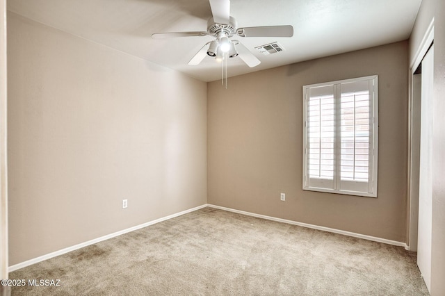 carpeted spare room featuring visible vents, a ceiling fan, and baseboards