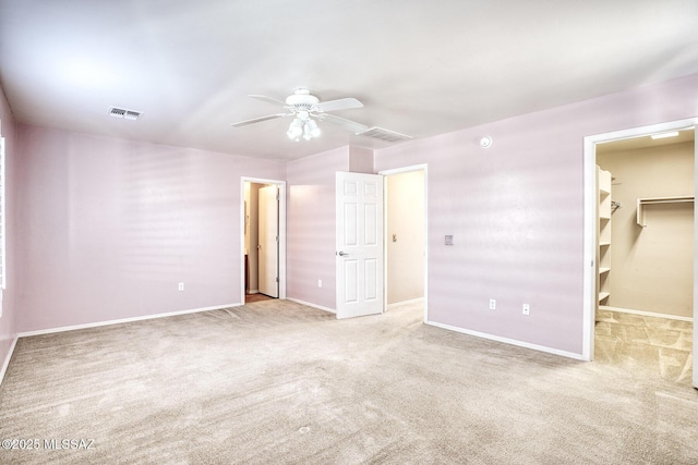unfurnished bedroom with a spacious closet, baseboards, carpet flooring, and visible vents
