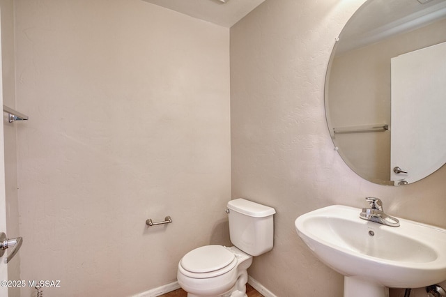 bathroom featuring a sink, baseboards, and toilet