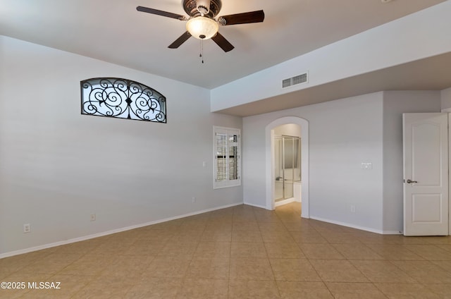 unfurnished room featuring arched walkways, ceiling fan, baseboards, and visible vents