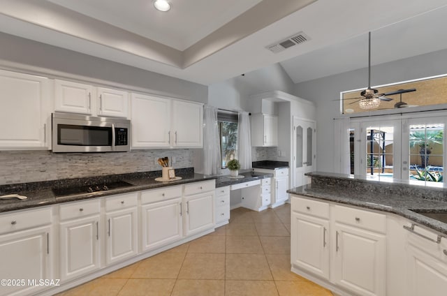 kitchen featuring stainless steel microwave, visible vents, decorative backsplash, and plenty of natural light