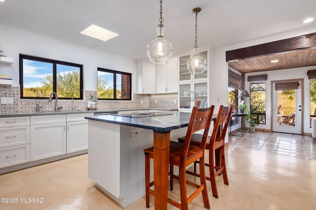 kitchen featuring a sink, a breakfast bar, a kitchen island, and white cabinetry