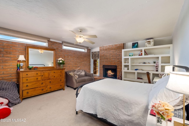 carpeted bedroom with a brick fireplace, a ceiling fan, and brick wall