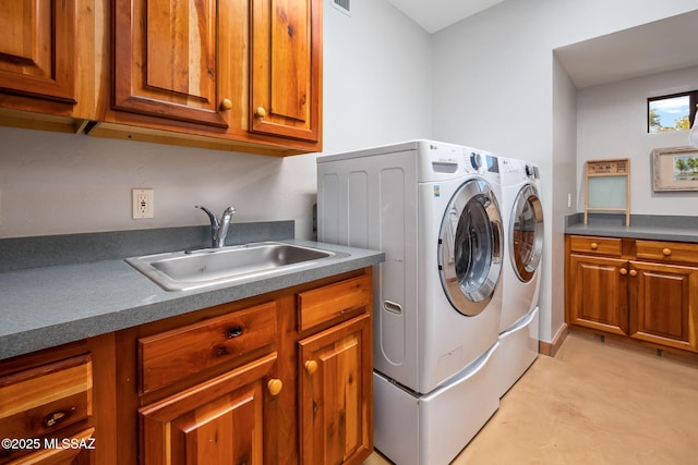 clothes washing area with cabinet space, washer and clothes dryer, and a sink