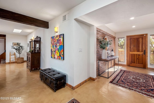 entryway featuring visible vents, concrete floors, baseboards, and beam ceiling