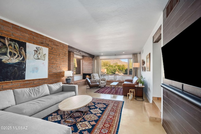 living area with a warm lit fireplace, concrete flooring, and brick wall