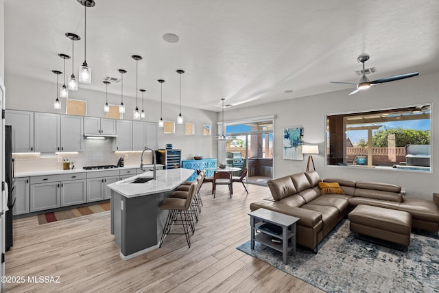living room featuring ceiling fan, light wood-style floors, and visible vents
