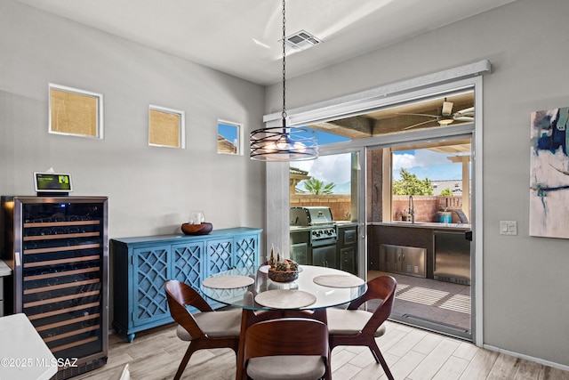 dining space featuring a wealth of natural light, visible vents, beverage cooler, and wood finished floors