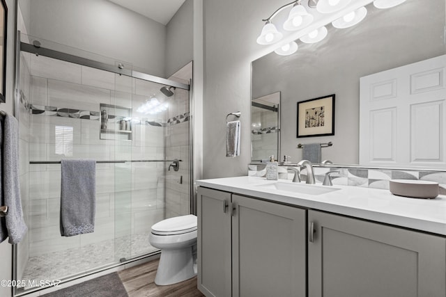 bathroom featuring toilet, a shower stall, vanity, and wood finished floors