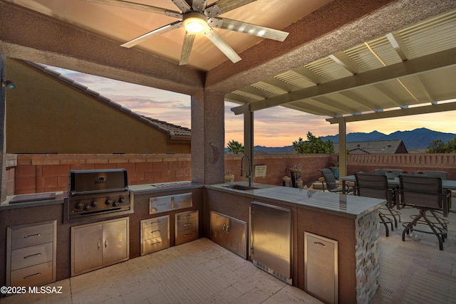 view of patio with a sink, fence, area for grilling, and a mountain view