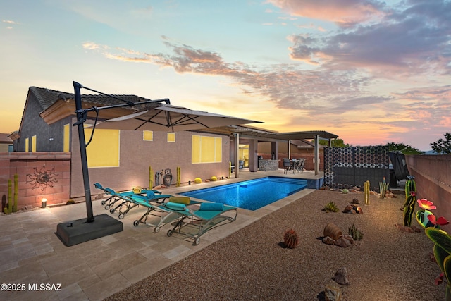 pool at dusk with a patio, a fenced in pool, and a fenced backyard