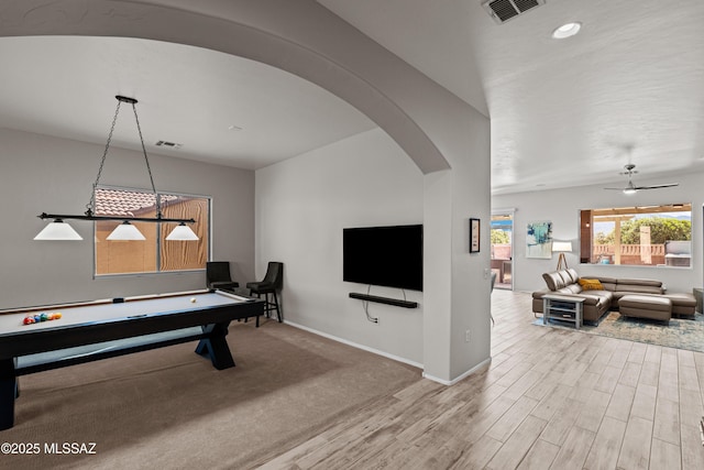 game room featuring visible vents, wood finished floors, baseboards, and arched walkways