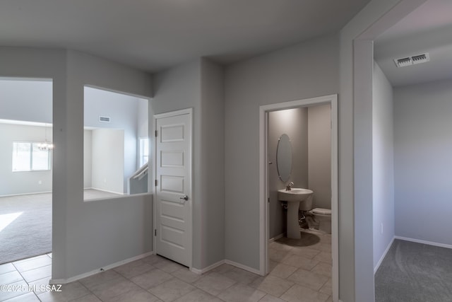 hall featuring visible vents, baseboards, and an inviting chandelier