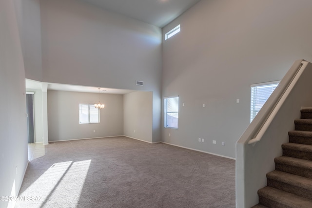 interior space with stairs, carpet flooring, a chandelier, and a towering ceiling