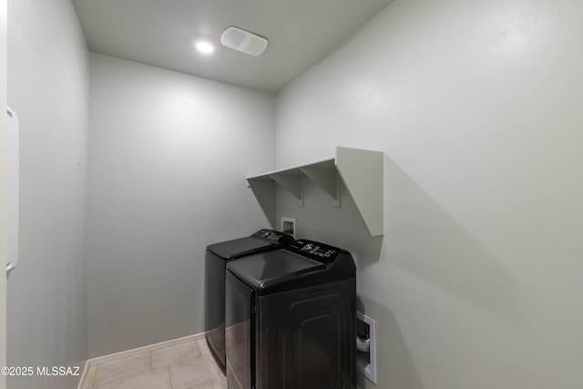 laundry room with light tile patterned floors, baseboards, laundry area, and washing machine and clothes dryer