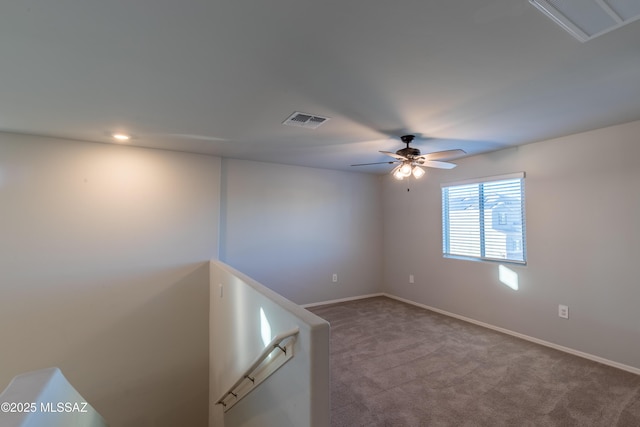 carpeted spare room with ceiling fan, visible vents, and baseboards