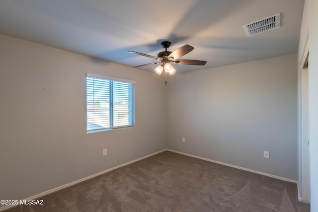spare room with baseboards, a ceiling fan, dark colored carpet, and visible vents