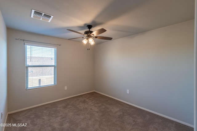 spare room with baseboards, ceiling fan, dark colored carpet, and visible vents