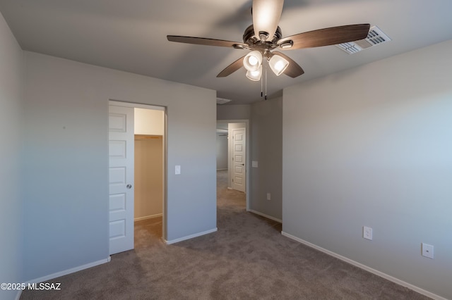 unfurnished bedroom featuring ceiling fan, visible vents, baseboards, a spacious closet, and carpet
