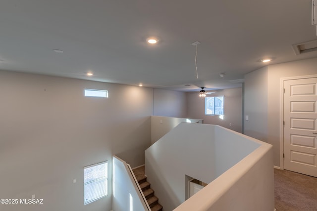 hallway featuring light carpet, recessed lighting, and an upstairs landing