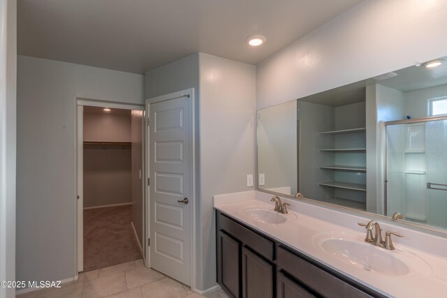 bathroom with a sink, a walk in closet, tile patterned flooring, and double vanity